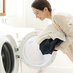 洗濯機を操作する女性の写真